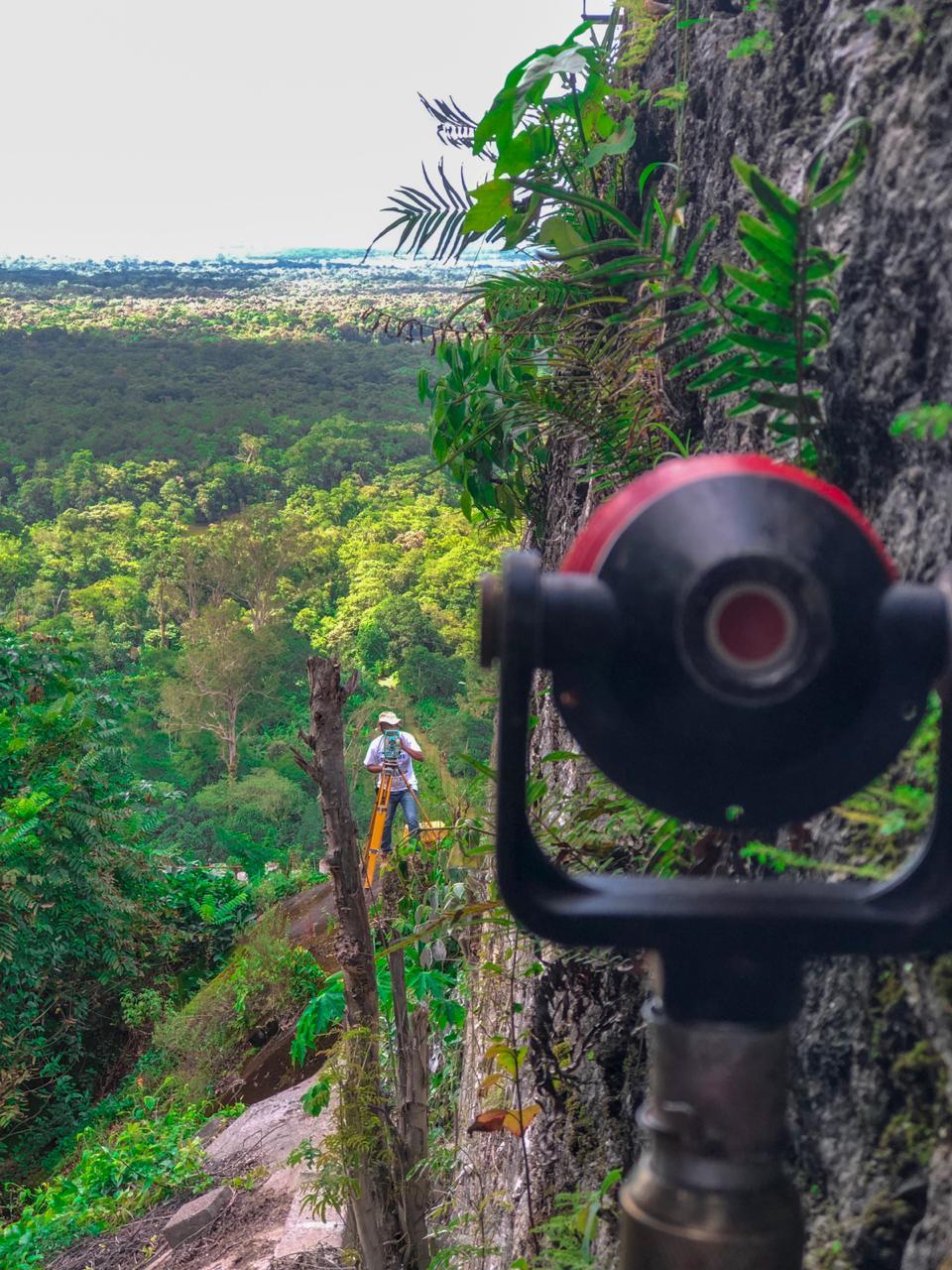 Foto com técnico topográfico mensurando local em aparelho Estação Total